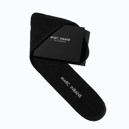 Marc Inbane Headband i svart mjukt material med vit märkning, utformad för att hålla håret på plats under självbruningsrutiner.