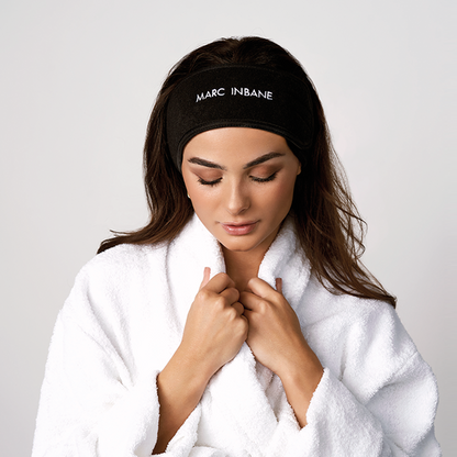 Kvinna med svart Marc Inbane Headband och vit morgonrock, perfekt vid applicering av self tanning för att hålla håret borta från ansiktet.